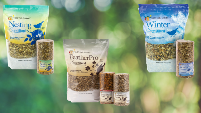 Bags and cylinders of Wild Birds Unlimited Nesting, FeatherPro, and Winter SuperBlend seasonal bird foods displayed against a green background.