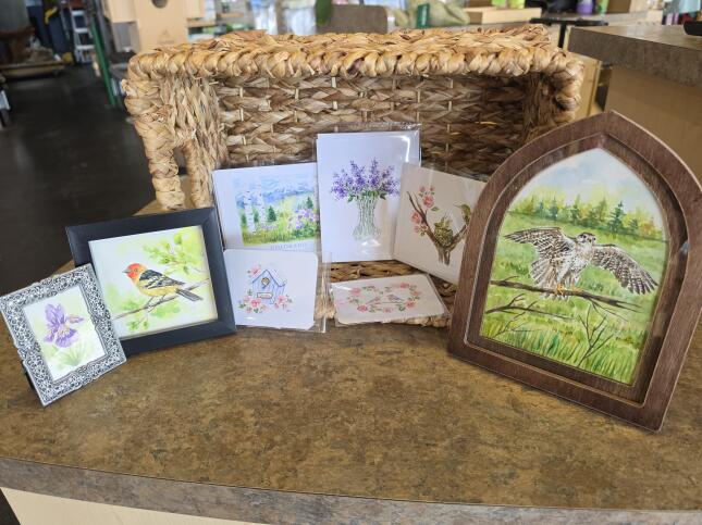 Framed watercolor paintings and greeting cards featuring birds, flowers, and Colorado scenery by local artist Cadence Finnicum of Watercolor Lane.